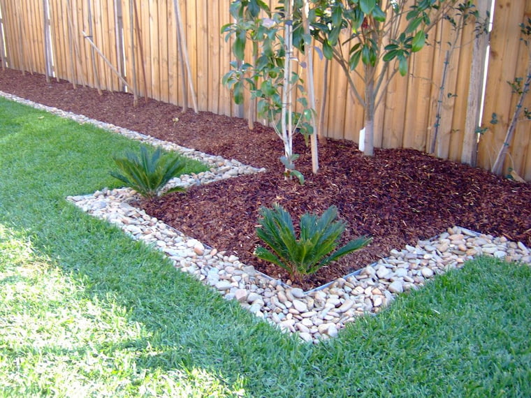 wood chips in garden with green grass and tree