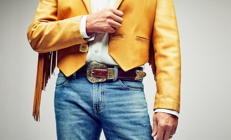 man wearing blue jeans with brown country belt and white shirt with yellow jacket