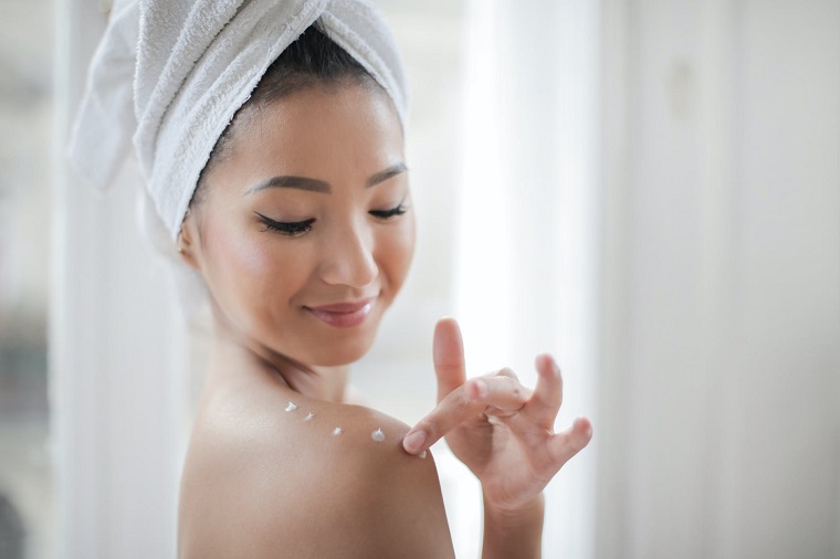 picture of a woman putting a moisturizer on her body 