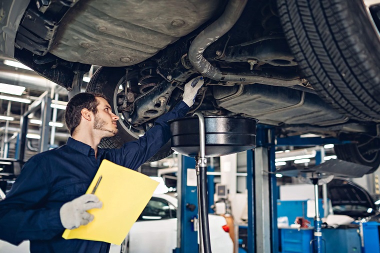 man looking at the bottom parts of a vehicle