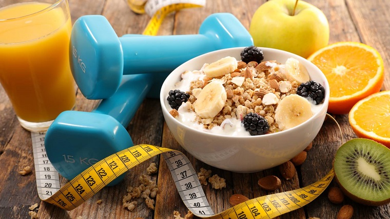 bowl of healthy food and weights on table to loose weight 