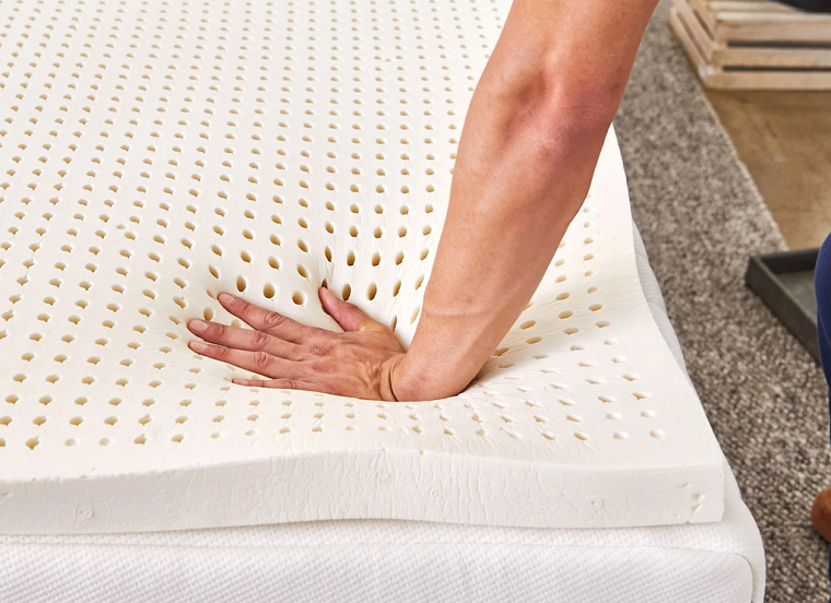 hand pressing down on latex mattress