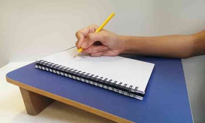 slant writing board with person's hand on it