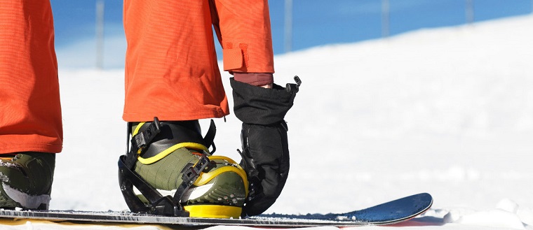man strapping in snowboarding bindings