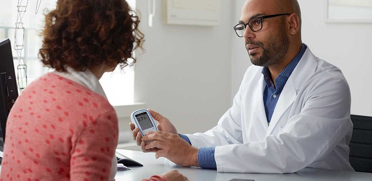 picture of doctor explaining an INR machine to a woman patient
