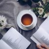 cup of black ceylon tea surrounded with white flowers and books