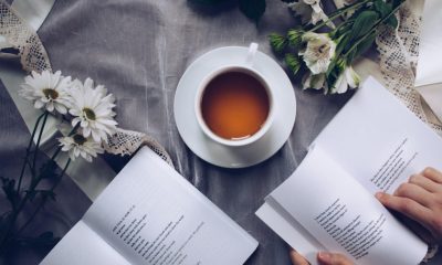 cup of black ceylon tea surrounded with white flowers and books