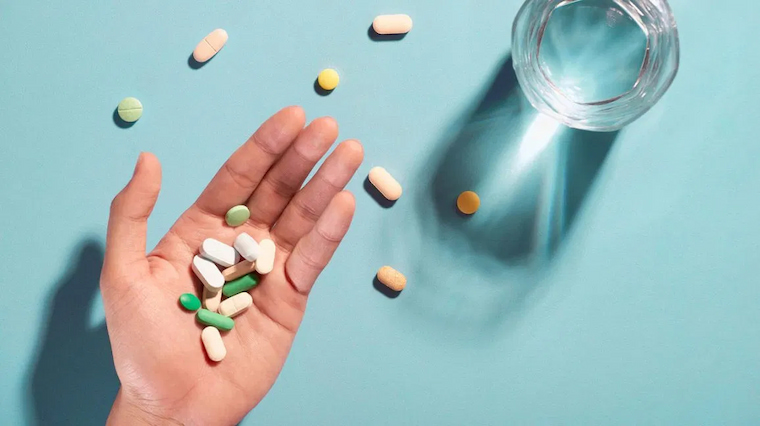 glass of water and hand full with magnesium pills