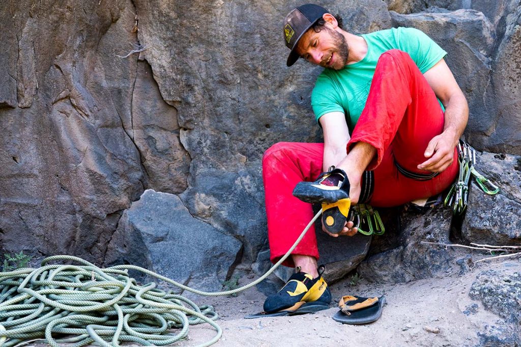 Man puts climbing shoes (slipper) on his feets, preparing for climbing