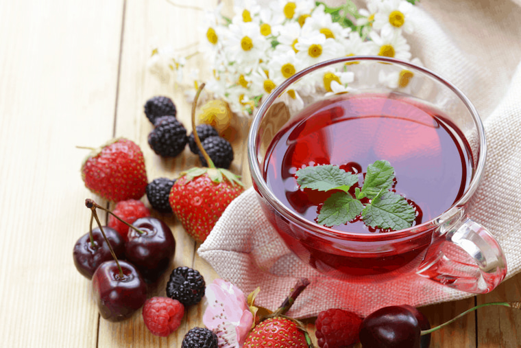 cup of fruit tisane tea surrounded with fruit
