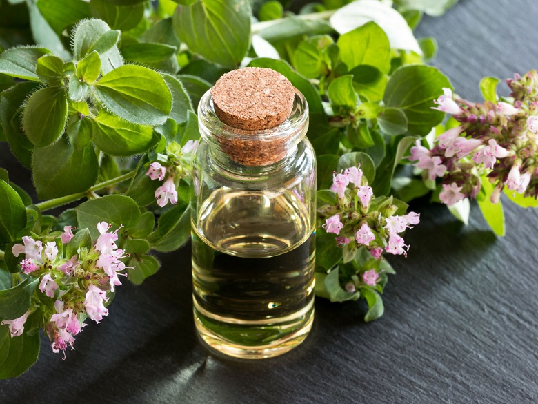picture of a essential oil beside a pile of oregano 