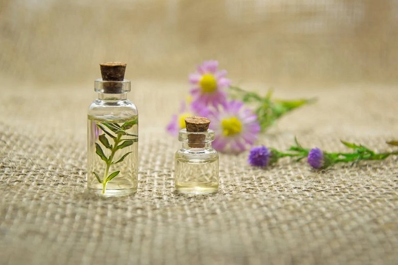 picture of bottles with essential oils beside flowers 