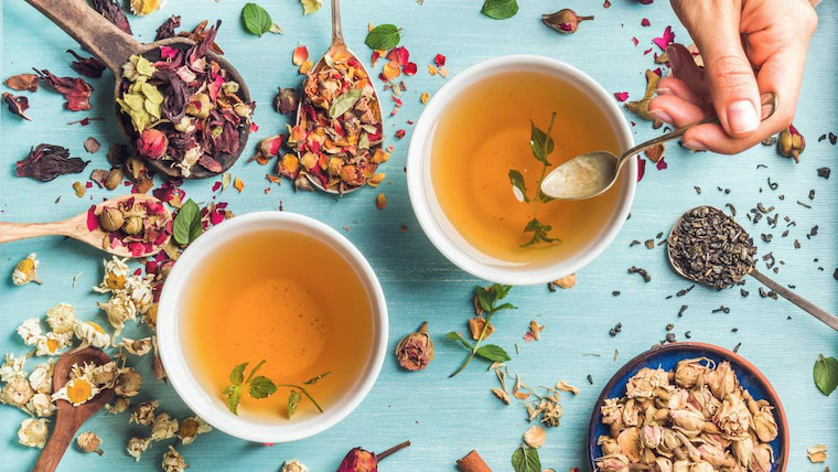 two cups of tisane tea surrounded with tea leaves