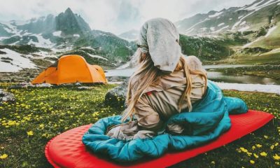 Woman sitting on a sleeping bag next to the lake