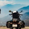 Man standing by his motorcycle with luggage on mountain