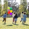 kids running in a yard with balloons