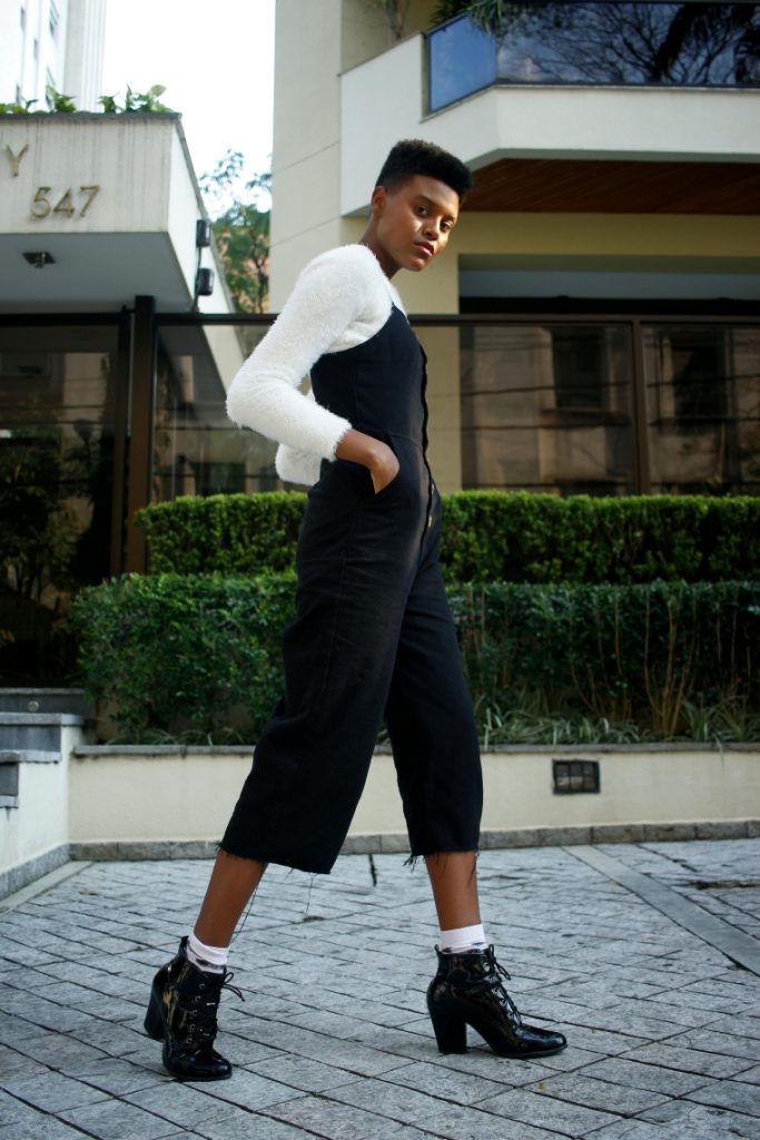 woman standing on the street wearing black jumpsuit for ladies with white top, black boots and white socks
