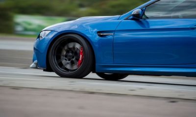 Close-up of a blue BMW sports car showing motion blur, focused on the front wheel with a performance brake system by Harrop